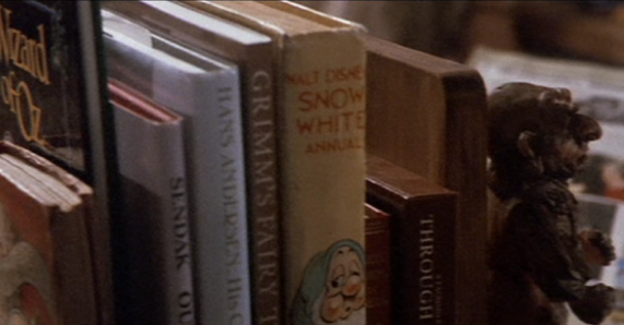 film still from Labyrinth depicting Sarah's books, including fairy tales and the Wizard of Oz, held up with a Hoggle shaped bookend