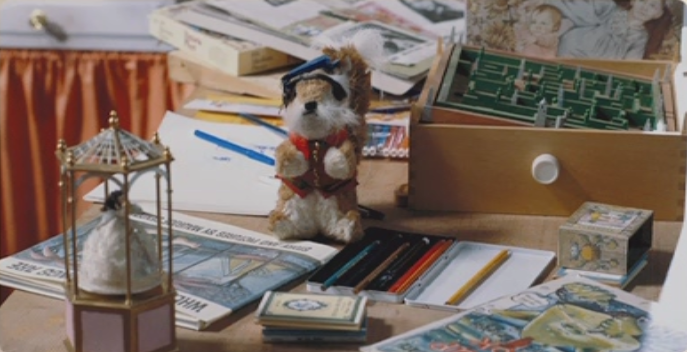 film still from Labyrinth depicting a messy desk covered in books and toys. A stuffed squirrel is dressed as Sir Didymus lies next to a maze