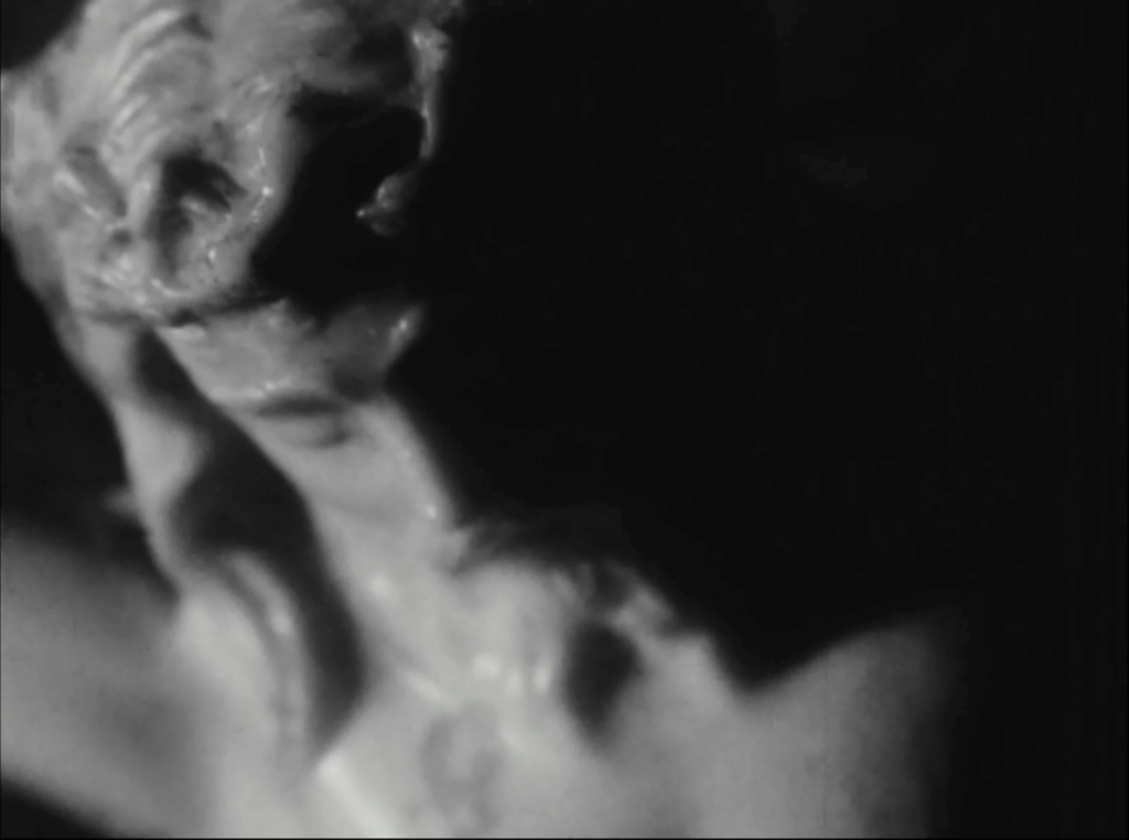 black and white film still depicting extreme close up of a crucifix, just Jesus's head is visible 