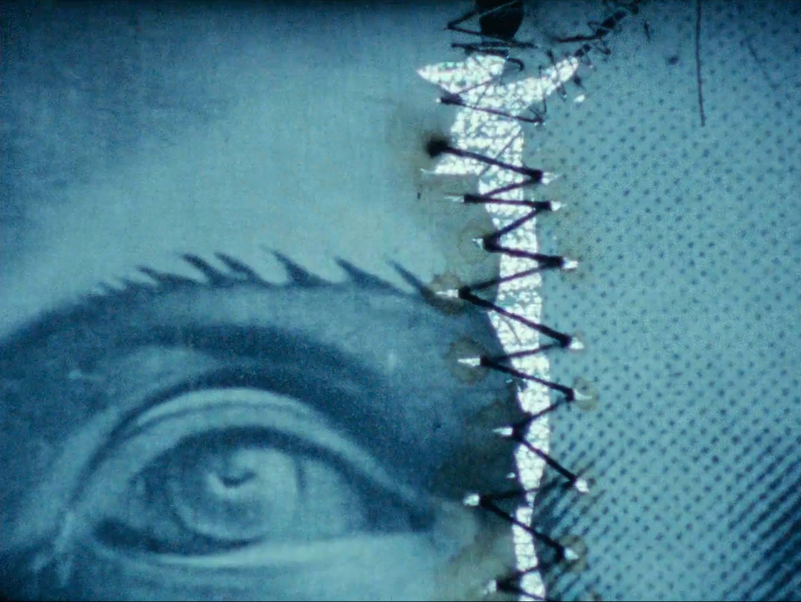 film still depicting physical collage sitting in front of a static-filled screen, giving the whole image a blue cast