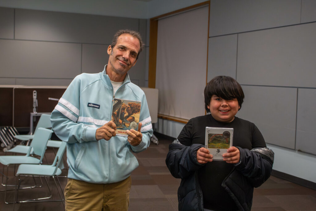 photo of a man and child, both holding DVDs and smiling at the camera
