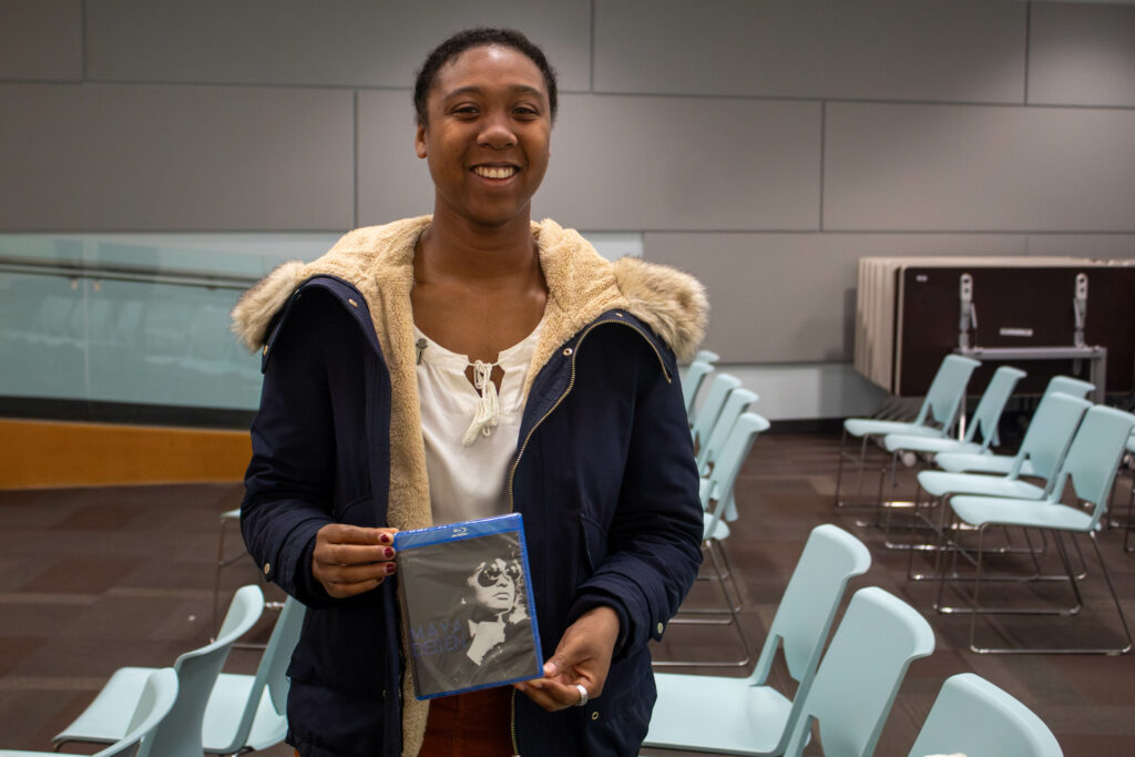 photo of woman standing and holding DVD while smiling at the camera