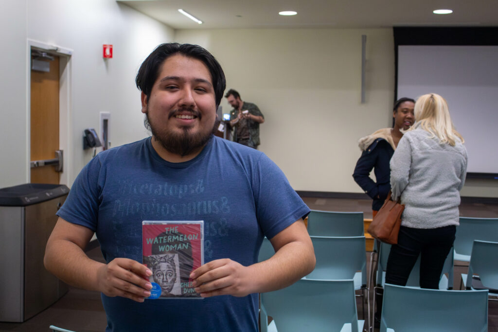 photo of a man standing holding a DVD and smiling at the camera