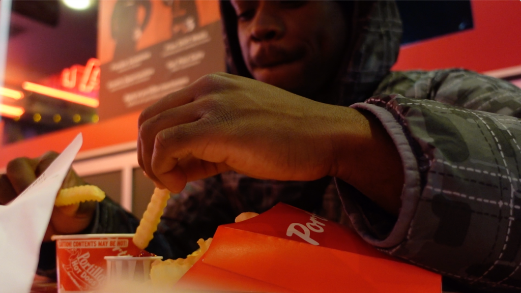 film still depicting close up of a man eating fries