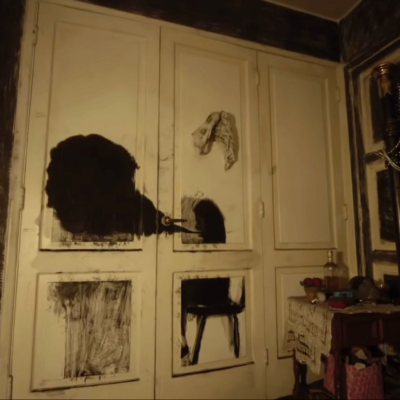 film still depicting messy charcoal drawing on a paneled wall