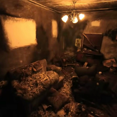film still depicting a dimly lit room, completely trashed and with blackened walls