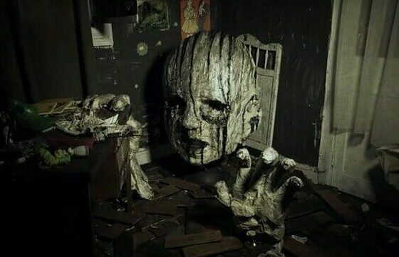 film still depicting a disembodied papier-mâché head and hand reaching out in a darkly lit room