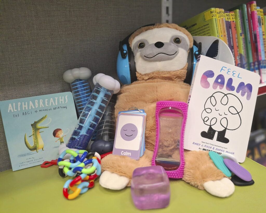 Plush sloth with headphones, sensory toys, kids books, and fidget items