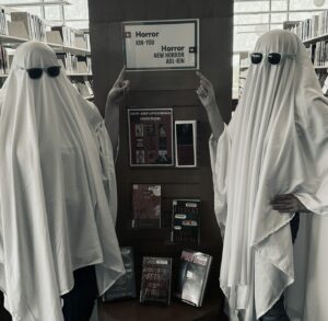 Two people dressed as ghosts pointing to the Horror collection