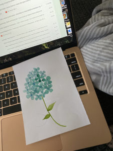 Watercolor of a flower on paper on a laptop