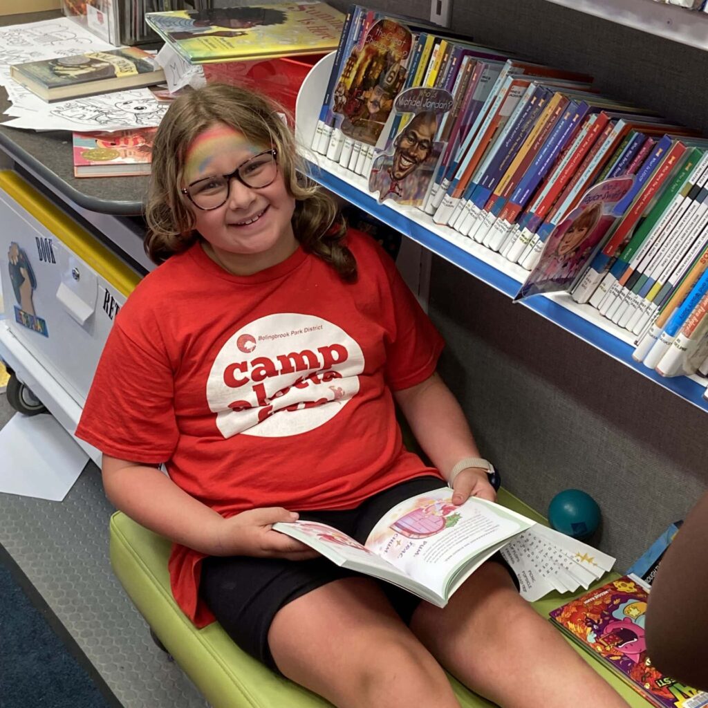 Girl sitting on the bench in the Bookmobile with a book open on her lap.
