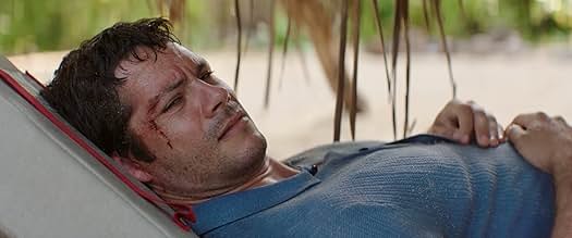 Dylan O'Brien with a cut on his cheek lies on a lounge chair outdoors