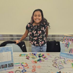 A girl stands behind a table