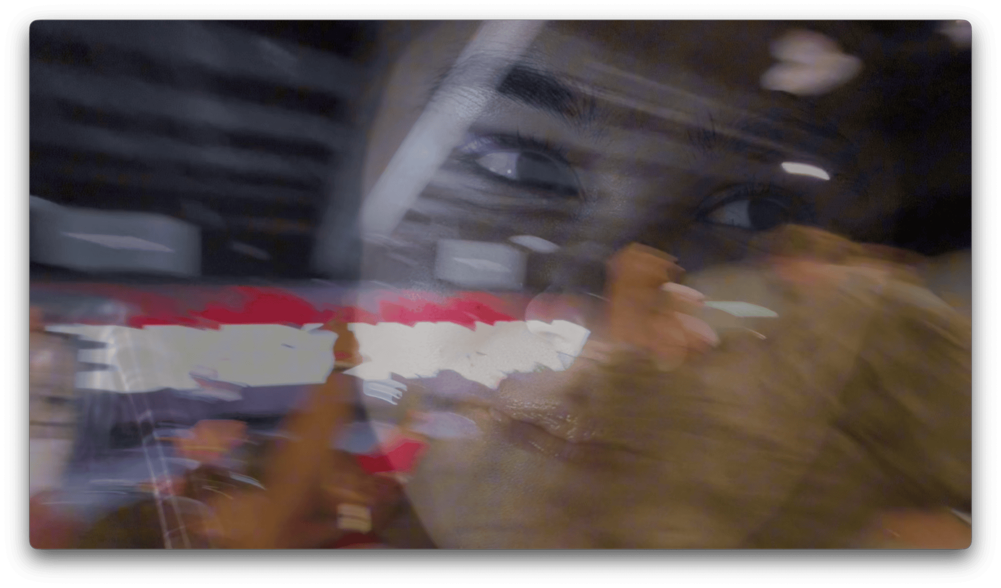 A blurred image shows a person's face superimposed over an indoor scene with bright lights and indistinct figures, creating a layered, abstract effect.